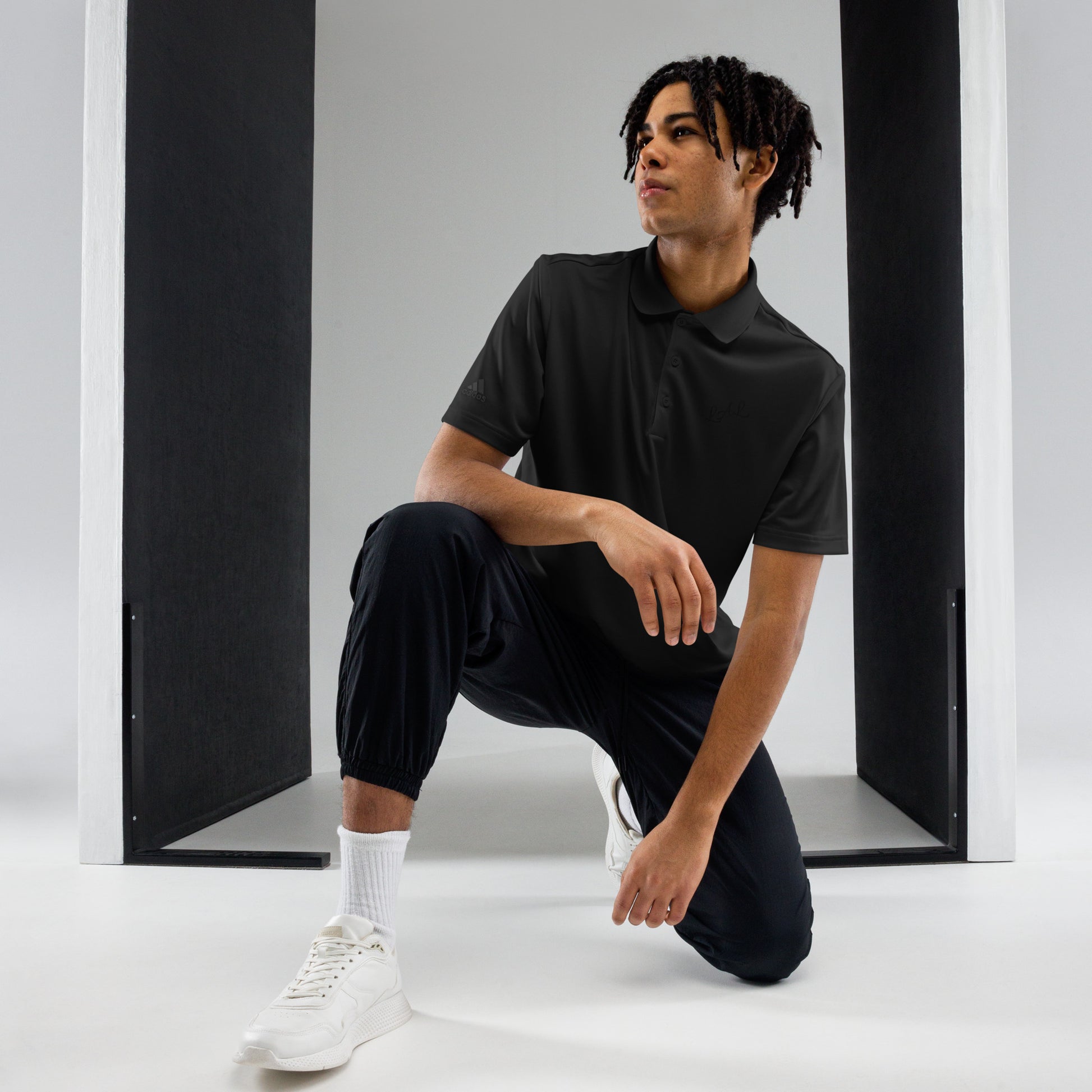 Man wearing black polo shirt and black jogger pants paired with white sneakers and socks