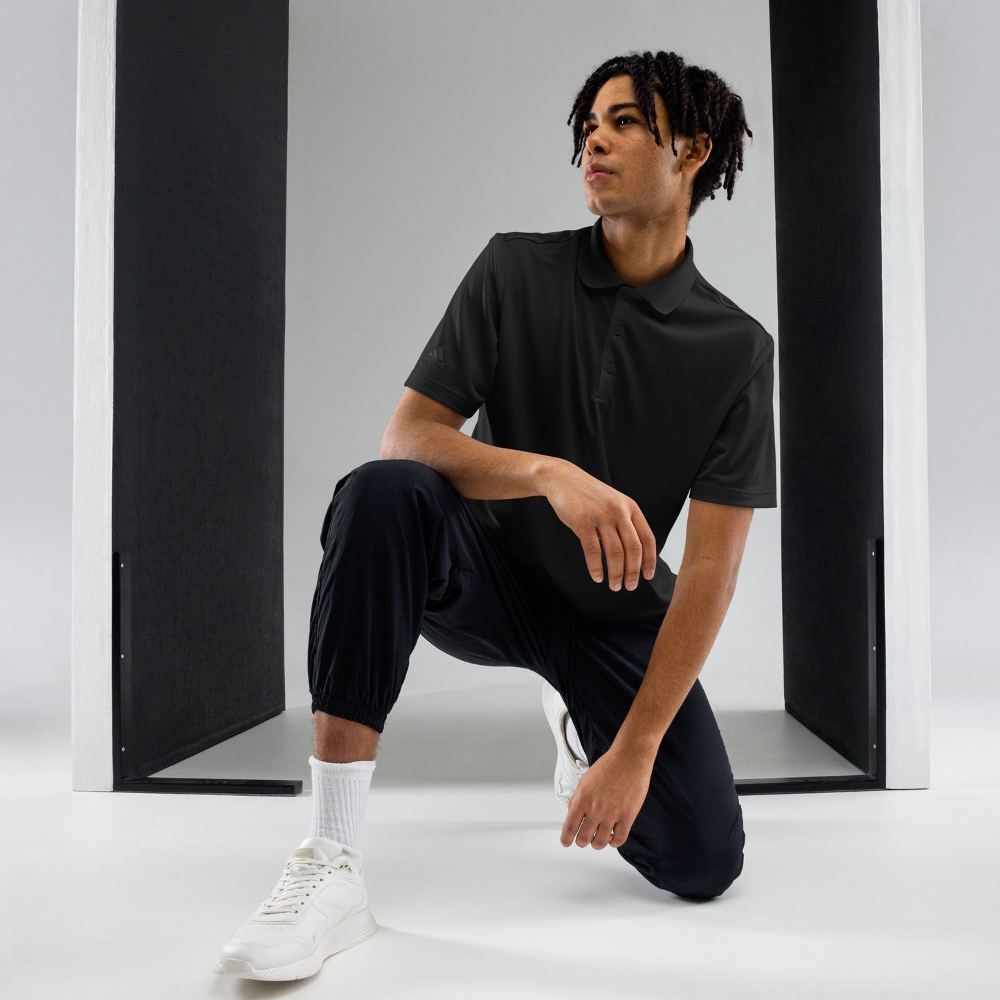 Man wearing black polo shirt and black jogger pants paired with white sneakers and socks
