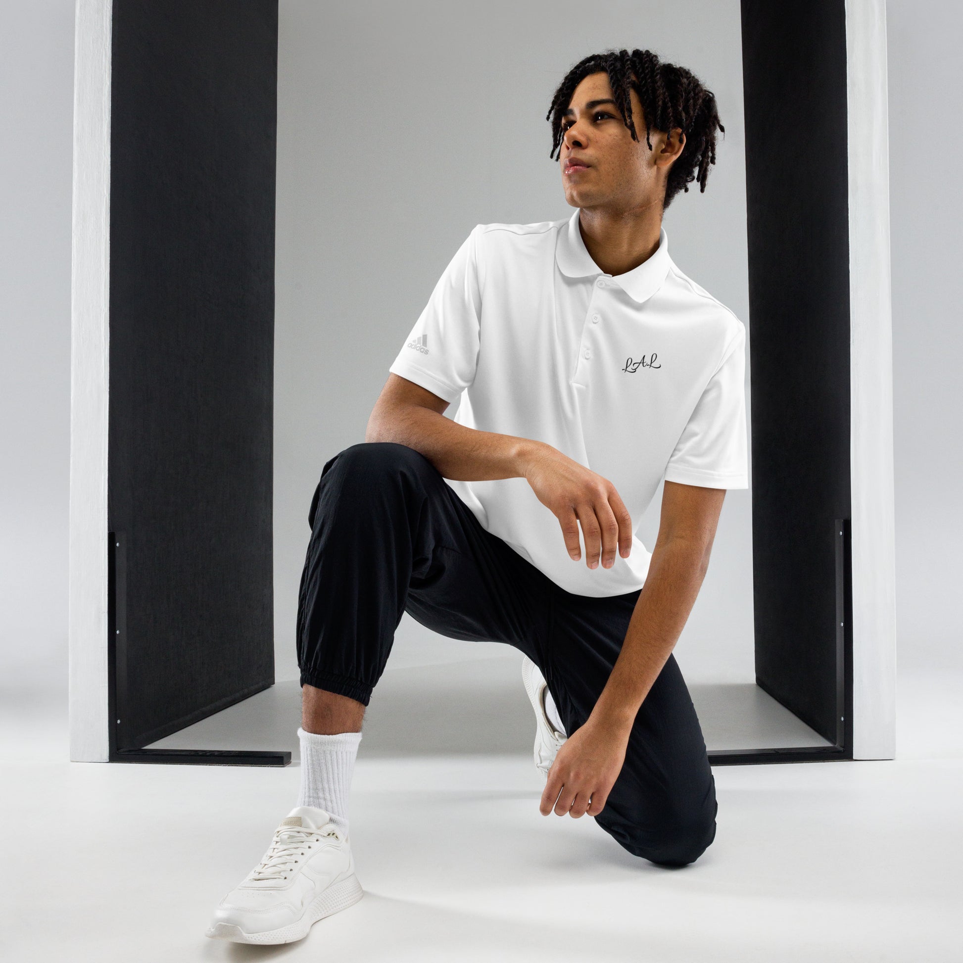 Man wearing white LAL Liberty123 polo shirt with black jogger pants and white sneakers