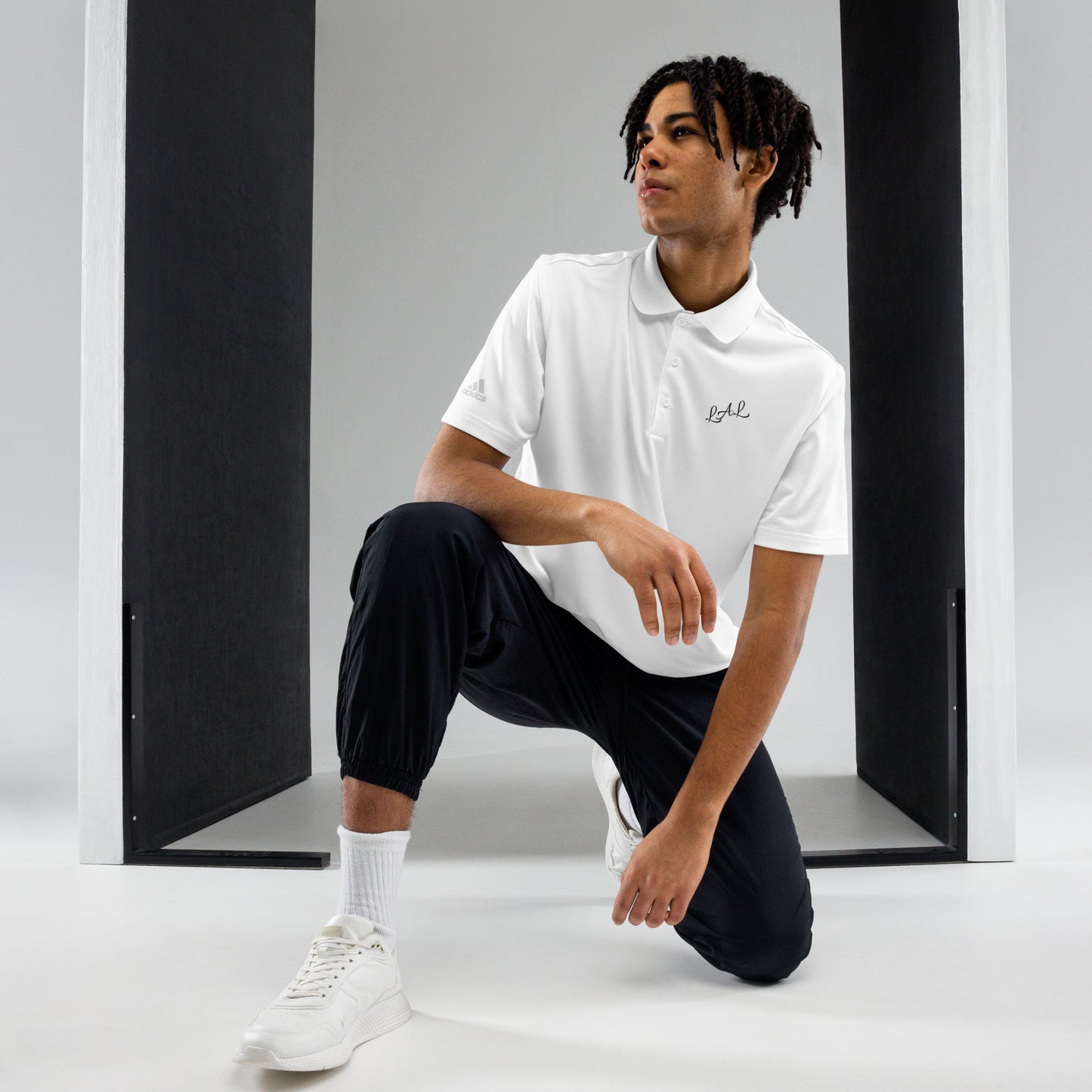 Man wearing white LAL Liberty123 polo shirt with black jogger pants and white sneakers